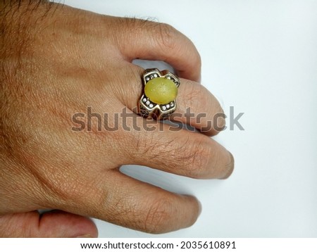 man's left hand wearing a silver ring with yellow opal