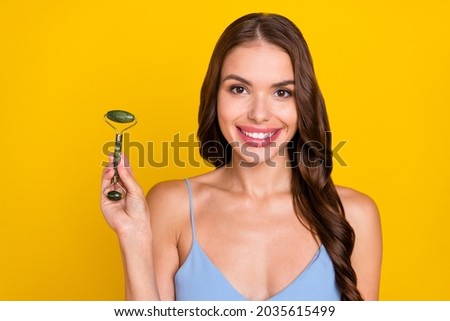 Photo of young woman happy positive smile roller jade face lifting rejuvenation isolated over yellow color background