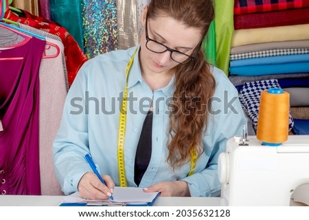 Creative female fashion designer draws sketches drafts. Lifestyle scene in a sewing Studio. Woman tailor creates drawings of fashionable dresses art