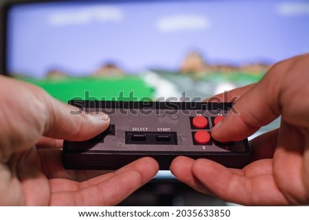 A man's hands hold a joystick in the background of a TV screen with a video game. Home entertainment concept