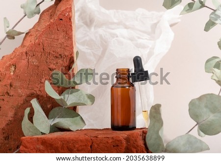 Mockup brown glass bottle with dropper serum on red stone and beige background with crumpled paper. Brutal. Copy space. Acid peeling, face oil, collagen.