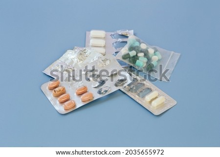 Stack of expired pills on blue background. Royalty-Free Stock Photo #2035655972