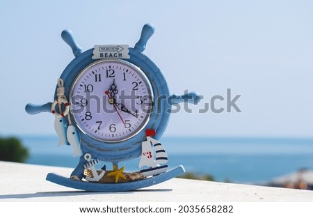A watch, a souvenir from the summer vacation. On the clock is the text "This way to the beach". Blue sea in the background. Royalty-Free Stock Photo #2035658282