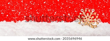 Snow on a red background, snowfall or falling snow. Large wooden snowflake in the snow. Christmas concept. New Year theme, panoramic photo for a banner or website header. Christmas card.