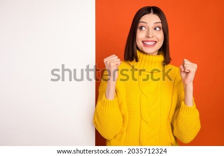 Photo of young woman happy positive smile rejoice victory success look empty space white wall isolated over orange color background