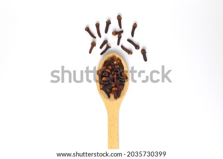 Dry cloves in wooden scoop isolated on white background with clipping path. Top view. Flat lay