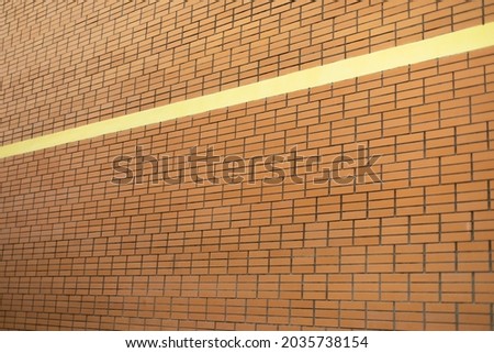 Brick wall of the house with a yellow stripe. Texture of bricks diagonally. Simple background masonry.