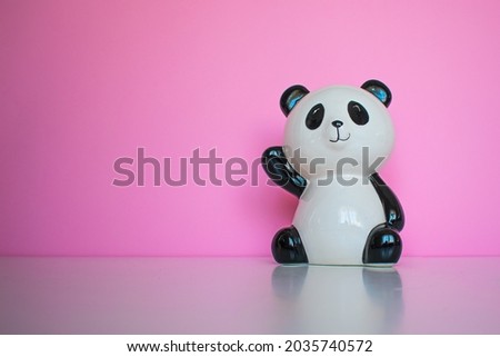Panda toy waving on a pink background. Happy panda  as a friend concept.