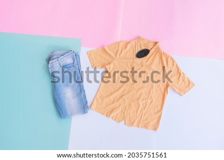 a yellow shirt and blue jeans on a background of various pastel colors
