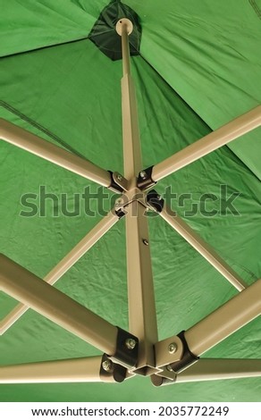 part of a large tent with metal part extention mechanism made of iron part on green cloth