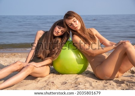 Two girls by the sea, swimwear in natural shades, khakki and beige