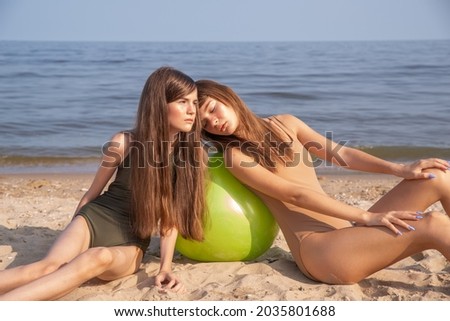 Two girls by the sea, swimwear in natural shades, khakki and beige