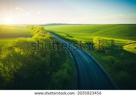 Drone flying over the rural road passing through agricultural land and cultivated fields. Top view drone shot. Agricultural area of Ukraine, Europe. Aerial photography. Beauty of earth.