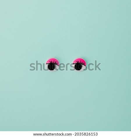 Small black eyes with lashes and pink eyelids on mint seafoam green background. Minimal design. Copy space.