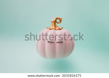 Pink Halloween fairy tale pumpkin with golden handle and eyelashes. Green mint background color. Minimal design.
