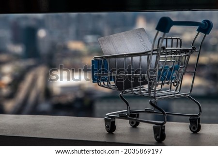 A credit card in a Mini supermarket trolley on Cityscape background. Ideas about home online shopping. Focus and blur.