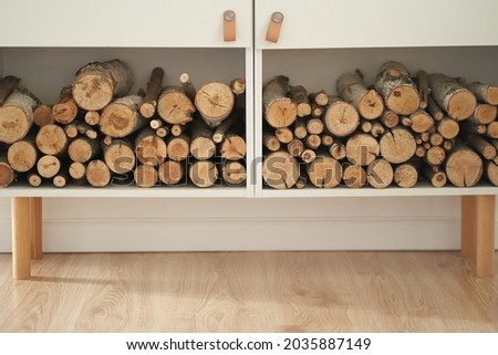 Stocks of firewood for the fireplace are stacked on the shelves. Background of dry chopped wood logs in a pile, on a white shelf. High quality photo