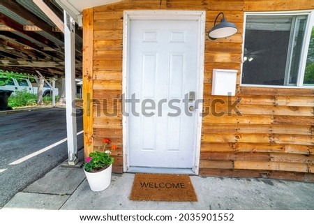 White front door decorated with flowers on a pot and doormat with welcome sign