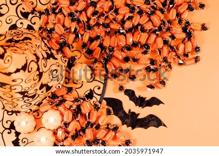 Halloween card - pumpkins, hat, candy and candles on an orange background for advertising, congratulations or sale