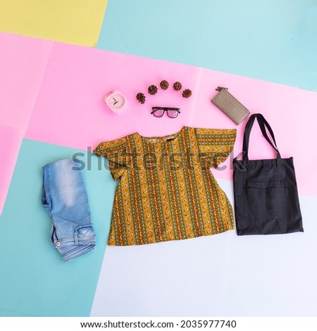 women's shirt, blue jeans, brown purse and black handbag on multi-colored pastel background. fashion background concept
