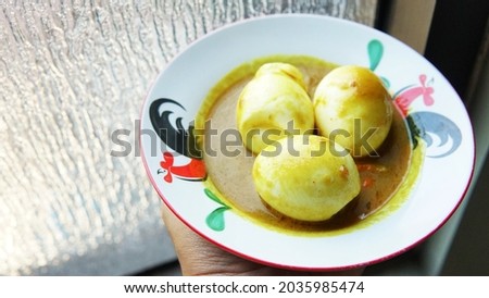 Boiled egg with curry sauce on a plate with a picture of a rooster                              