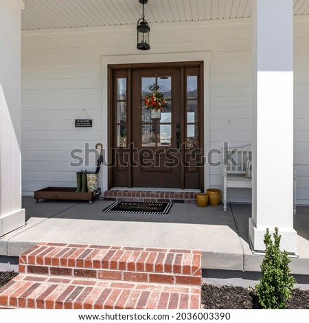Square frame Exterior of a house with brick stairs, plants and white walls Royalty-Free Stock Photo #2036003390