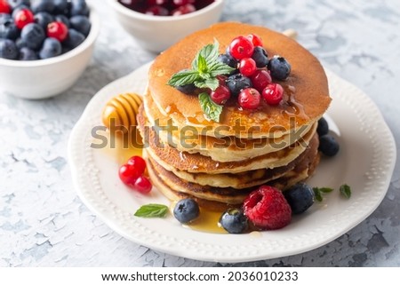 Healthy summer breakfast, homemade classic american pancakes with fresh fruit and honey, morning light gray stone background copy space top view Royalty-Free Stock Photo #2036010233
