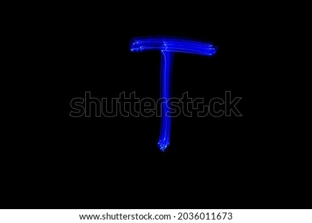 Letter T. Light painting alphabet. Long exposure photography. Drawn letter T with blue lights against black background.