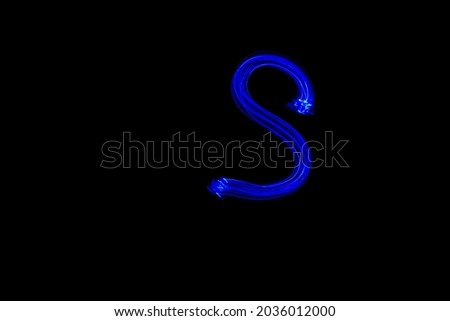 Letter S. Light painting alphabet. Long exposure photography. Drawn letter S with blue lights against black background.
