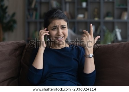 Unhappy Indian woman talking speaking on smartphone, hearing bad news, dissatisfied customer arguing or complaining, feeling disappointed, worried young female making phone call, solving problem Royalty-Free Stock Photo #2036024114