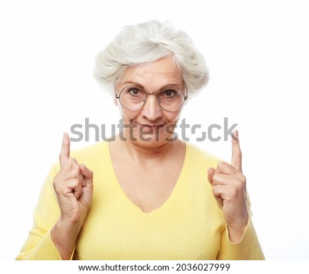 Portrait of a happy senior woman pointing upwards, isolated on a white background
