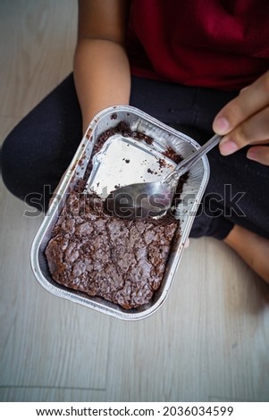 Brownies in a aluminum tray being eaten by a person. High angle view.