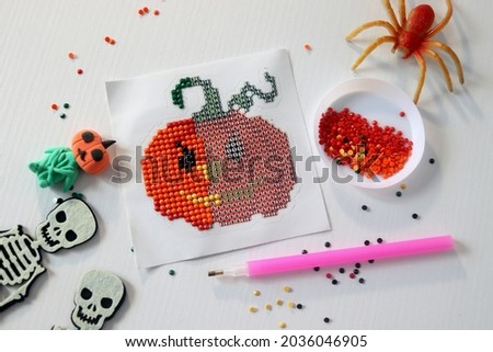 picture in the shape of a funny pumpkin diamond mosaic intermediate process selective focus, kids crafts,