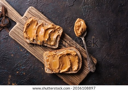 Sweet peanut paste or butter with honey on bread for tasty breakfast on dark concrete background