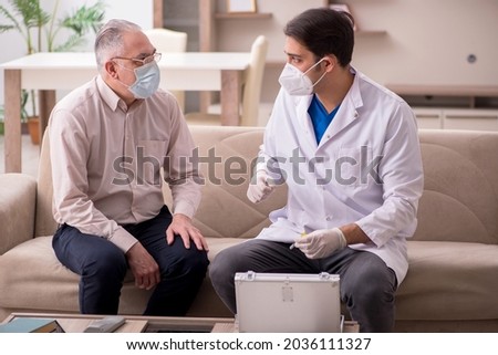 Young male doctor visiting old patient in vaccination concept Royalty-Free Stock Photo #2036111327
