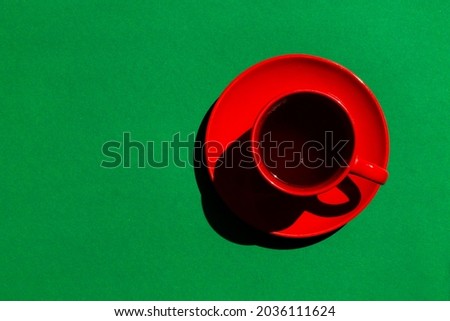 top view of red cup and saucer with black tea or coffee on the green background. copy space.