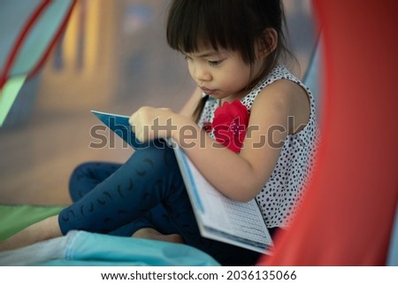 1 Asian girl, age 3 years old, enjoying a cartoon picture book.