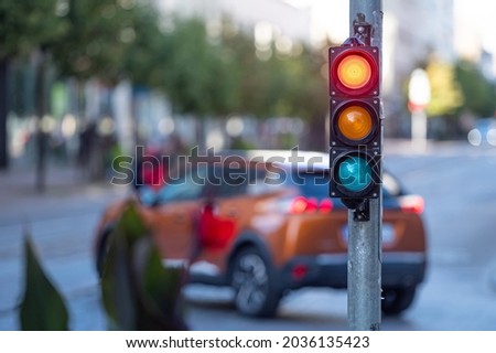 blurred view of city traffic with traffic lights, in the foreground a semaphore with a red light Royalty-Free Stock Photo #2036135423