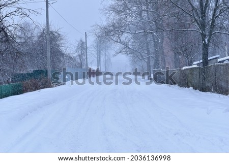 The street of the village is covered with snow.