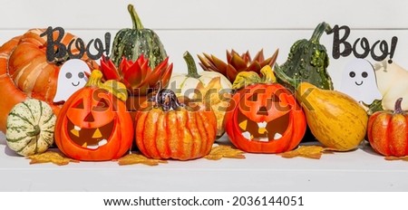 Happy Halloween! Pumpkin Jack on the table. Lantern with a carved smile and different attributes of the holiday on a light background.A copy of the place for the text.