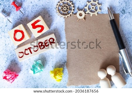OCT 5, yellow cube calendar on blue wooden surface with copy space
