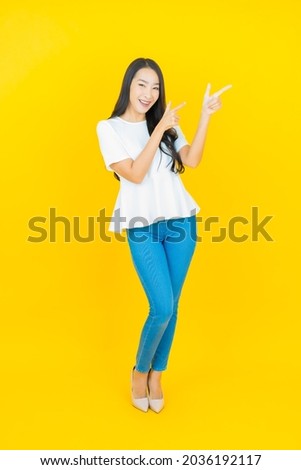 Portrait beautiful young asian woman smile with action on yellow color background