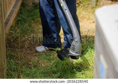 A person using a weed eater to trim the weeds in a yard.