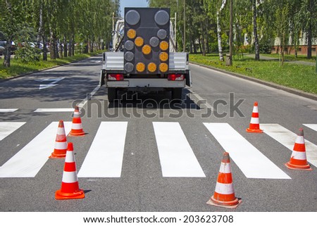 Road construction site with signs and orange road hazard cone