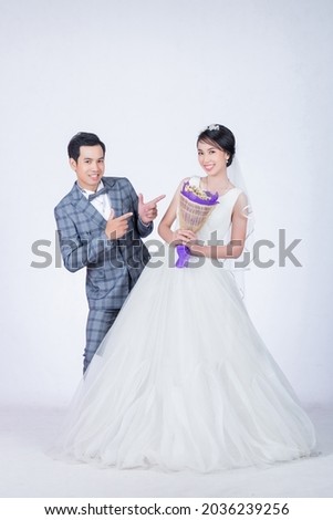 portrait of playful groom and beautiful bride on wedding day on isolated white background in studio Royalty-Free Stock Photo #2036239256