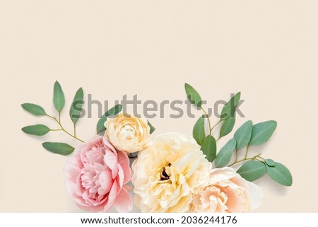 Pastel peony and ranunculus flowers on light orange background