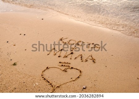 Declaration of love on the sand of the beach. Lettering names equals love