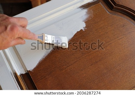 a brown kitchen cabinet is painted with white chalk paint  Royalty-Free Stock Photo #2036287274