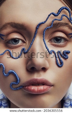 Macro portrait of woman in blue wire mask. Creative accessories on marine theme                                            