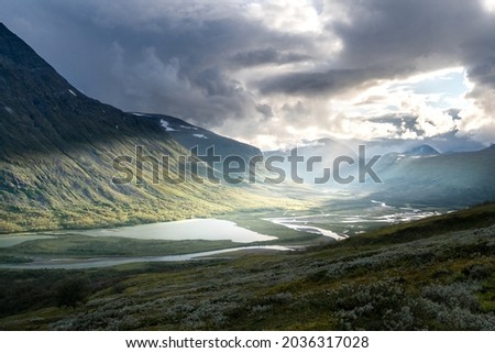 Remote harsh arctic landscape in rough weather in Sarek national park, Swedish Lapland. Heavy clouds with rays of light coming through Royalty-Free Stock Photo #2036317028